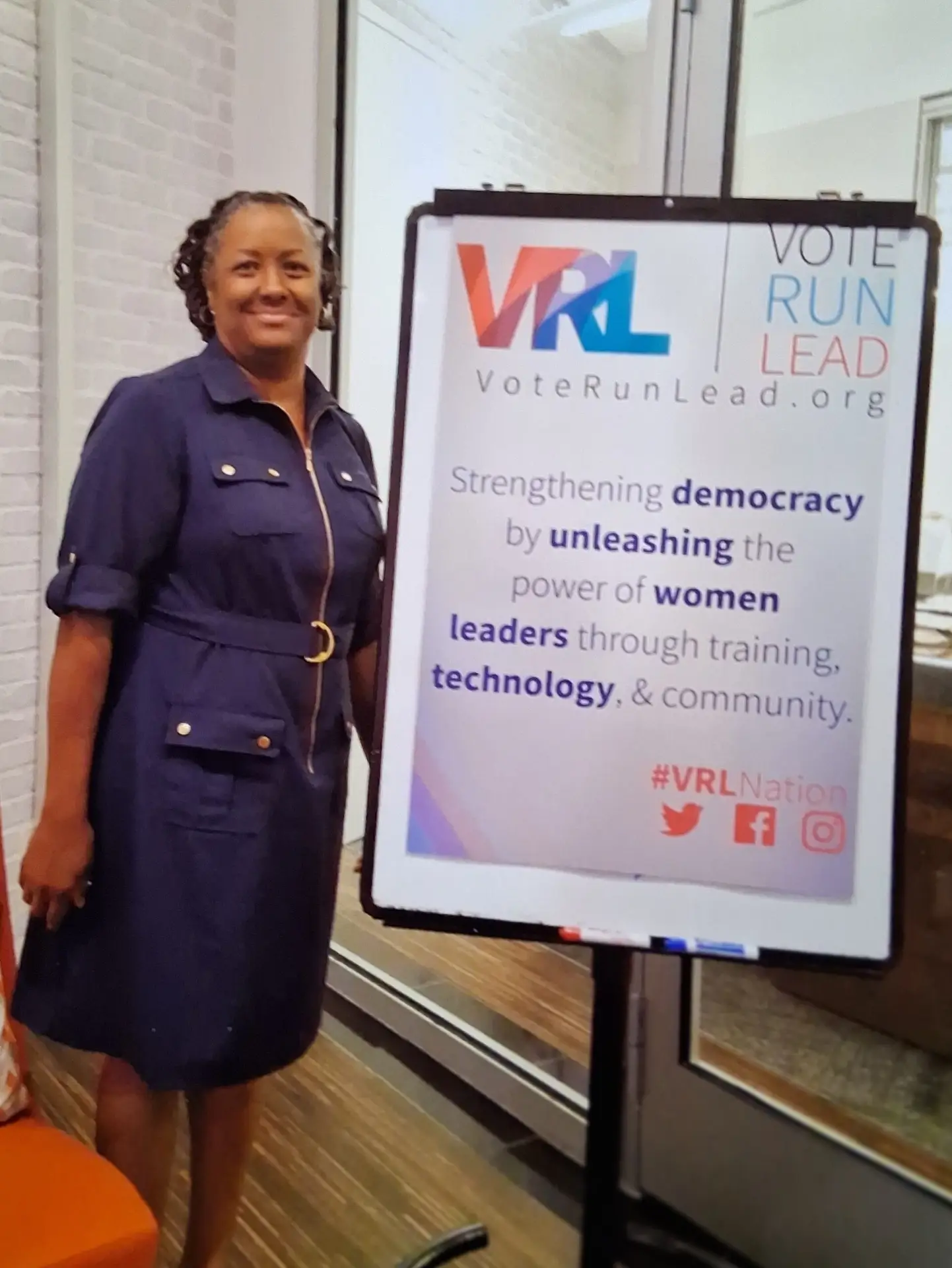 Sheila is standing next to a VoteRunLead.org poster